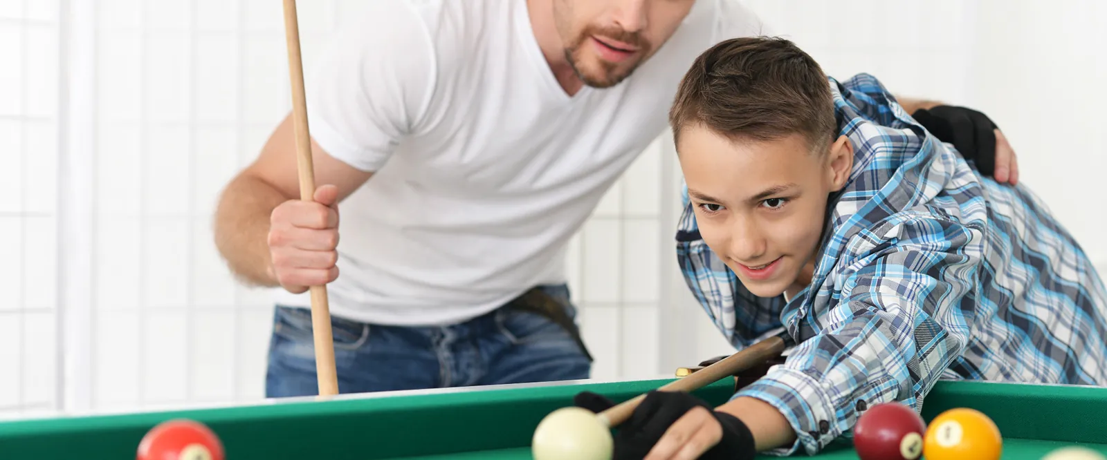 Otec učí syna hrát kulečník u chytrého jídelního stolu doma